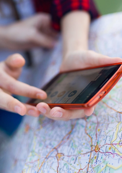 landkort og en der holder mobiltelefon i sine hænder