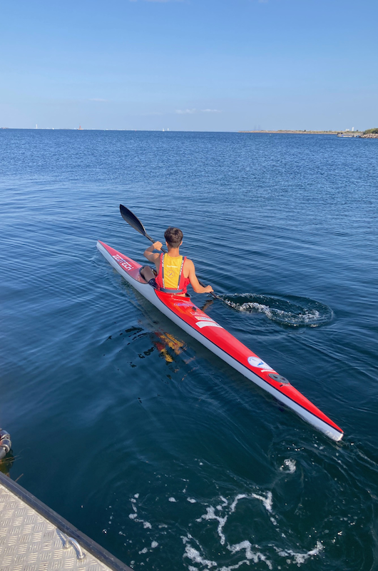 rød kajak med barn i på havet