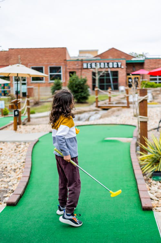 barn på minigolfbane med golfkølle i hånden