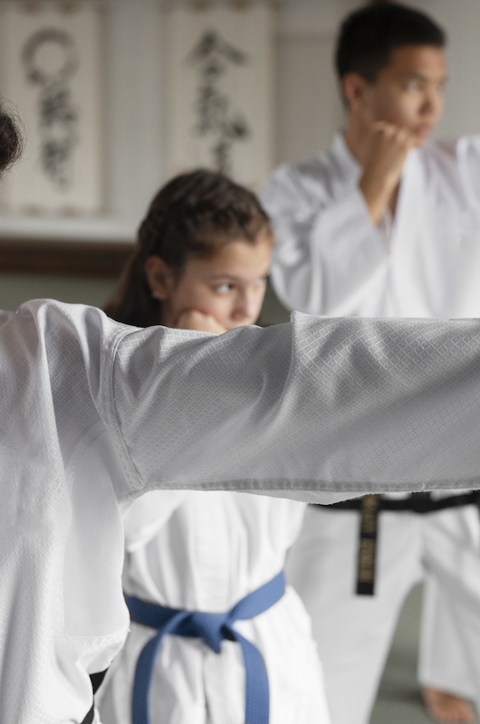 store børn i hvide karate dragter laver karatebevægelse